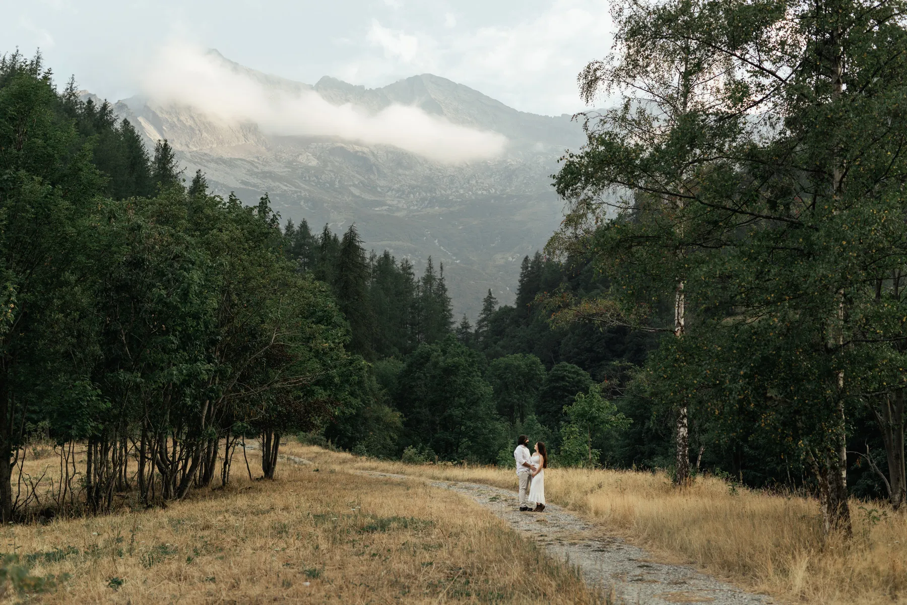 Coppia in attesa su un sentiero tra bosco e montagne