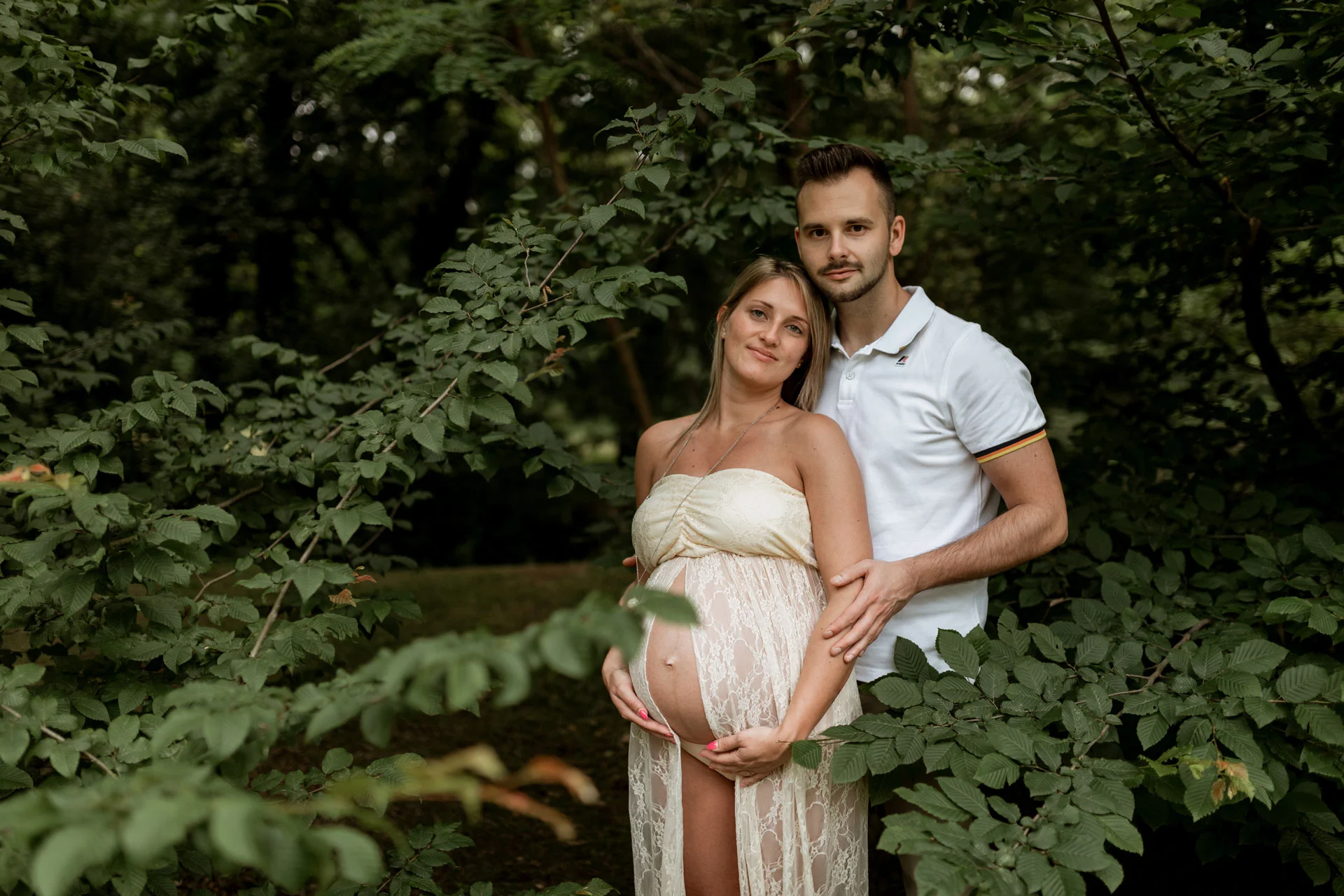 Ritratto di coppia durante l’attesa Futuri genitori abbracciati nel verde durante un servizio fotografico di gravidanza