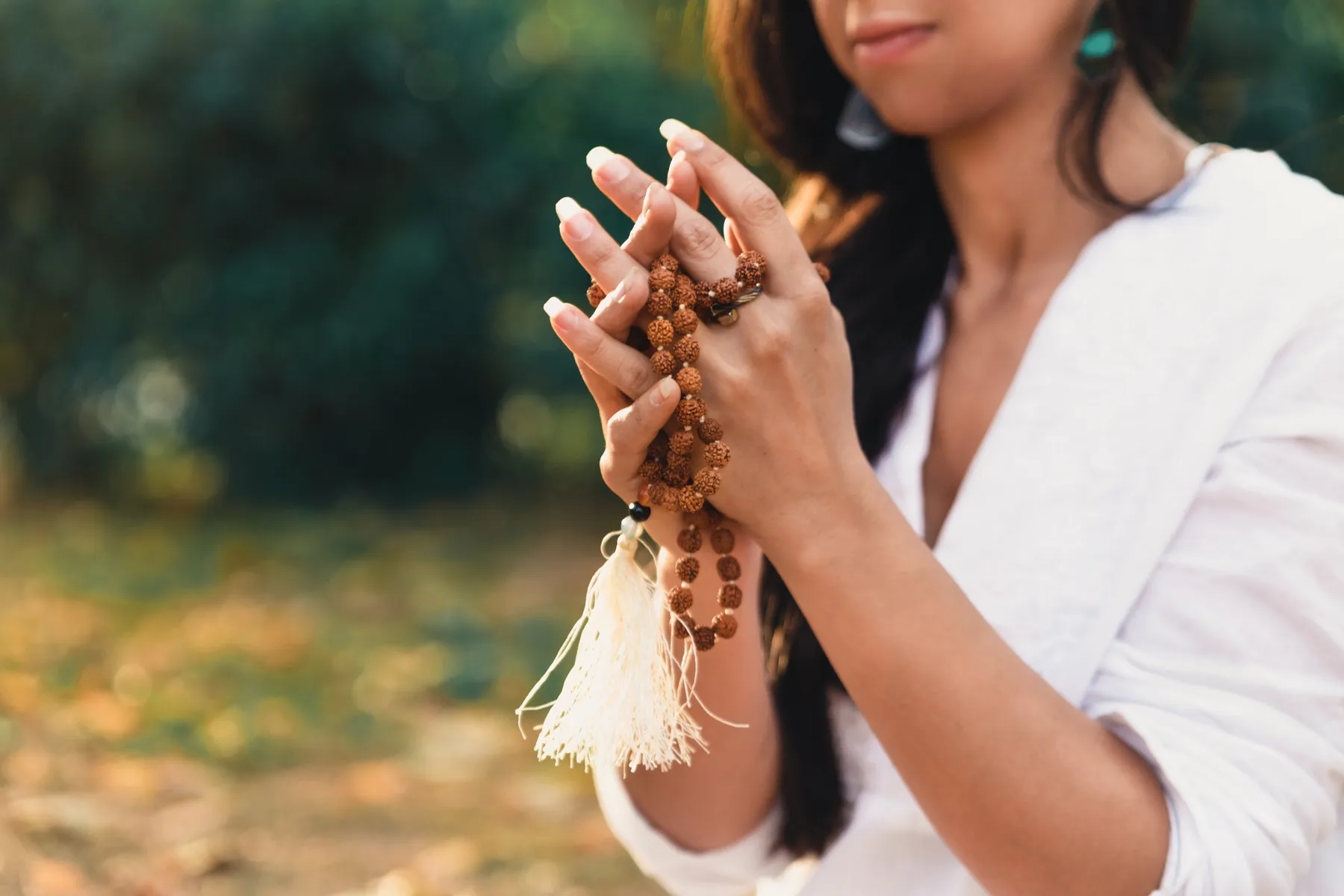 Dettaglio delle mani di una donna con un mala da meditazione