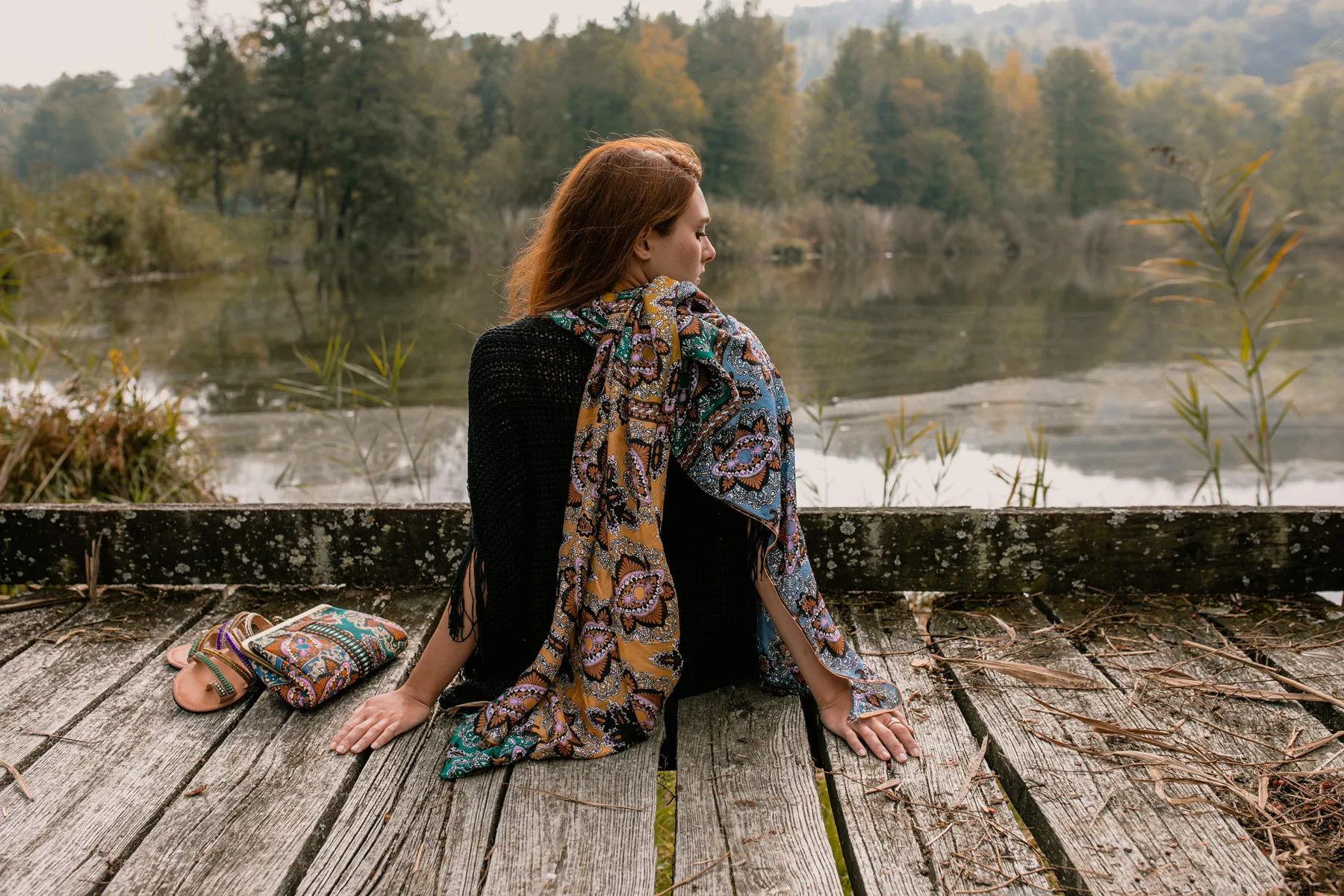 Editorial moda con outfit fantasia al lago Modella con outfit fantasia fotografata di spalle davanti a un lago