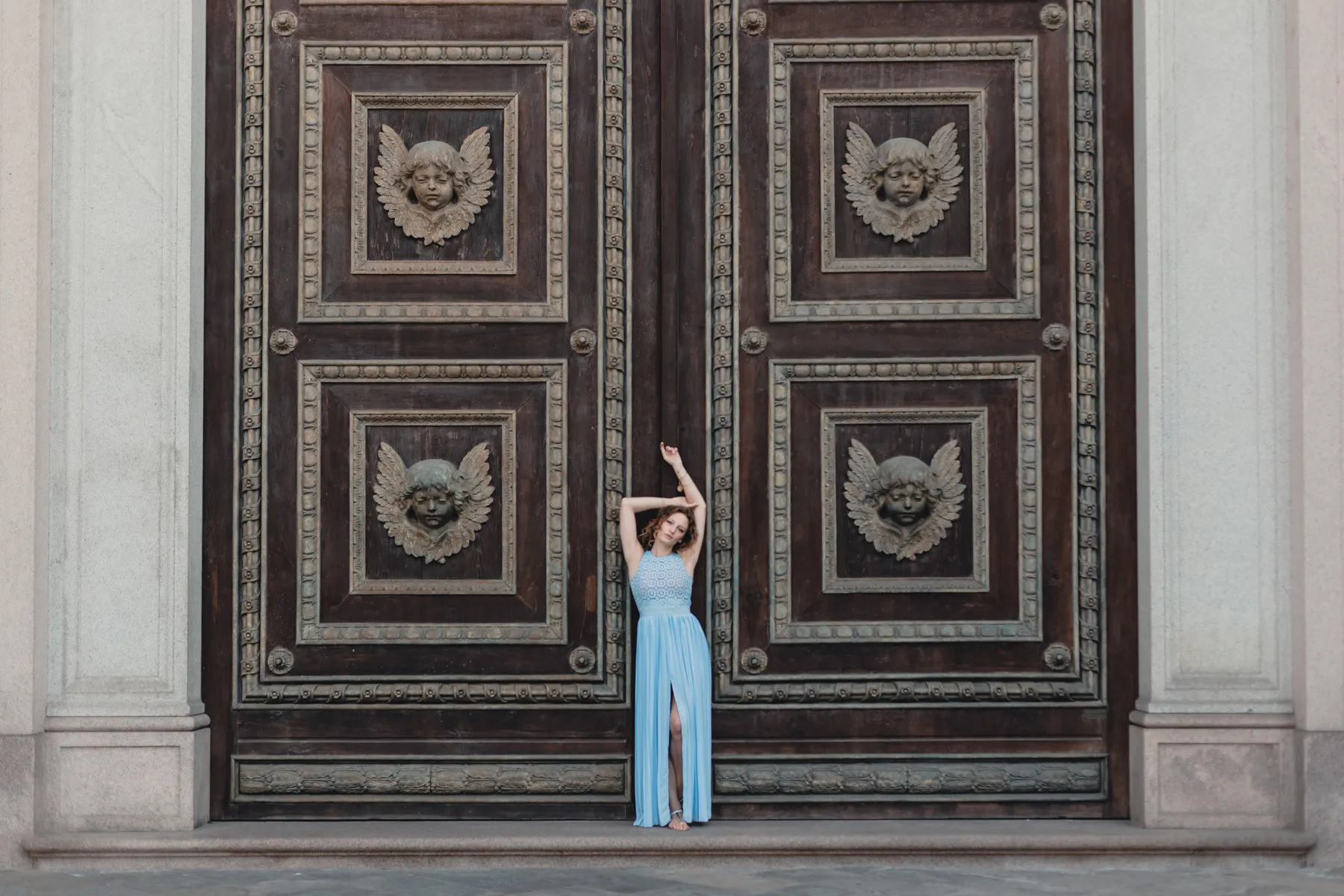 Fotografia moda con abito azzurro a Torino Modella con abito azzurro fotografata davanti a un grande portone storico di Torino