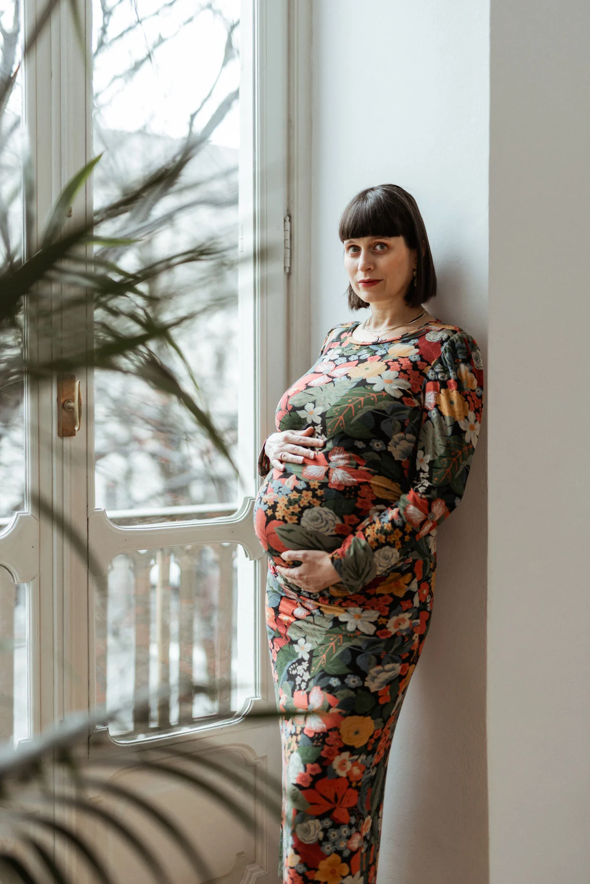 Servizio fotografico di gravidanza a casa Donna in gravidanza fotografata accanto alla finestra durante un servizio maternity a casa