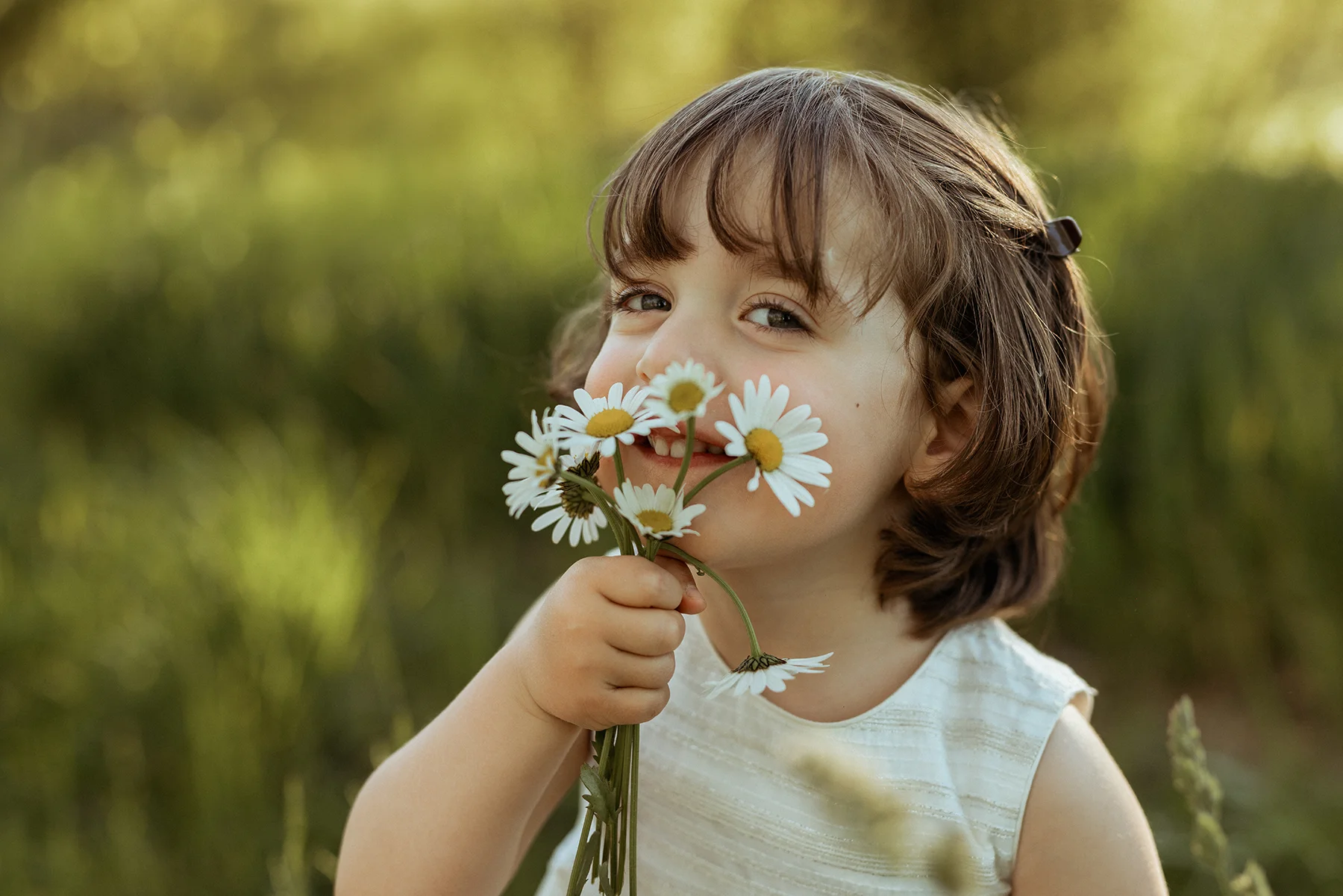 Bambina con un mazzo di margherite durante un servizio fotografico all'aperto