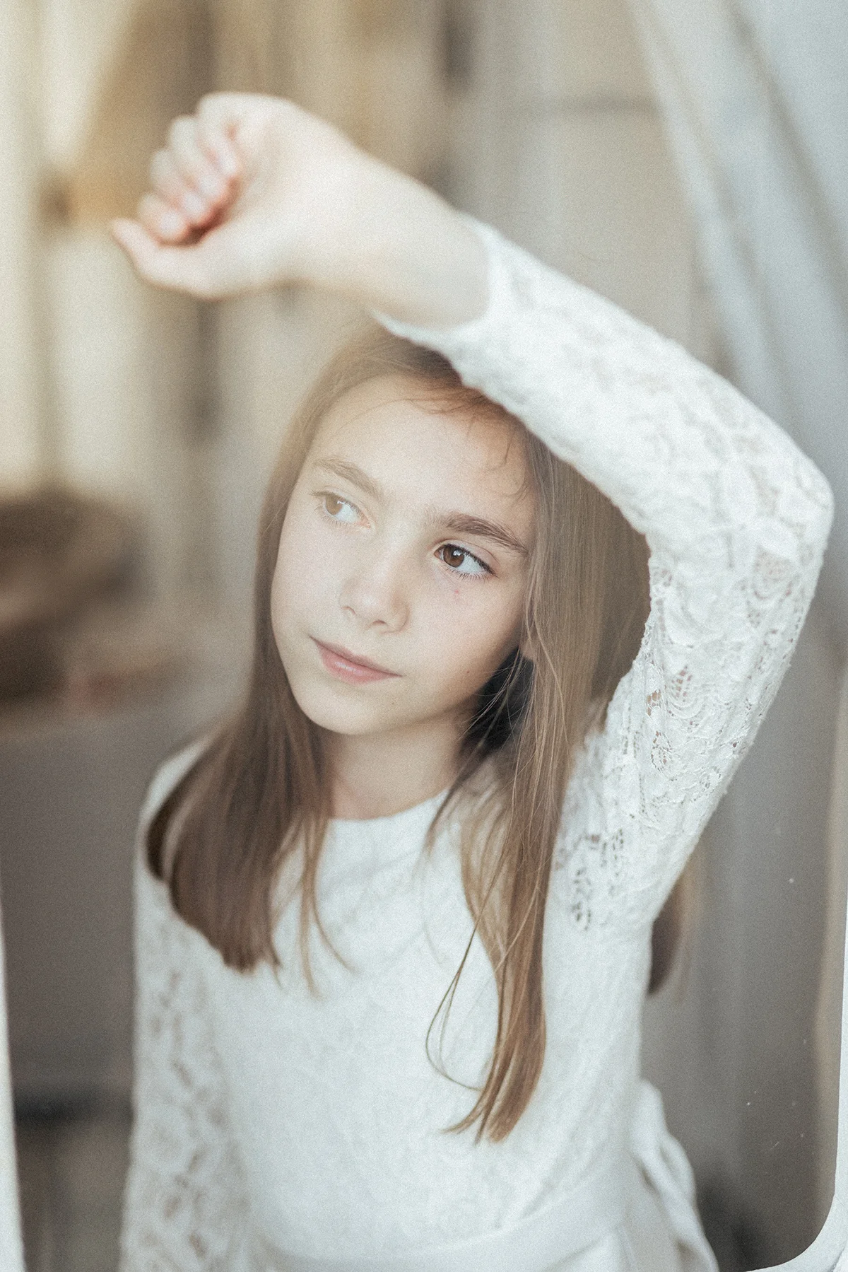 Ragazza in abito bianco fotografata nella luce della finestra