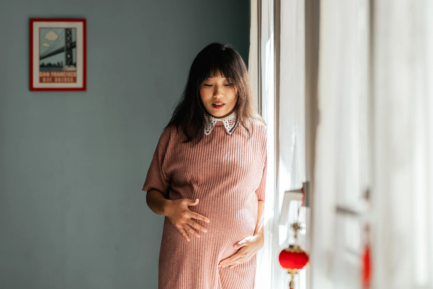 Ritratto di maternità in casa Donna in gravidanza ritratta in casa accanto a una finestra durante un servizio maternity