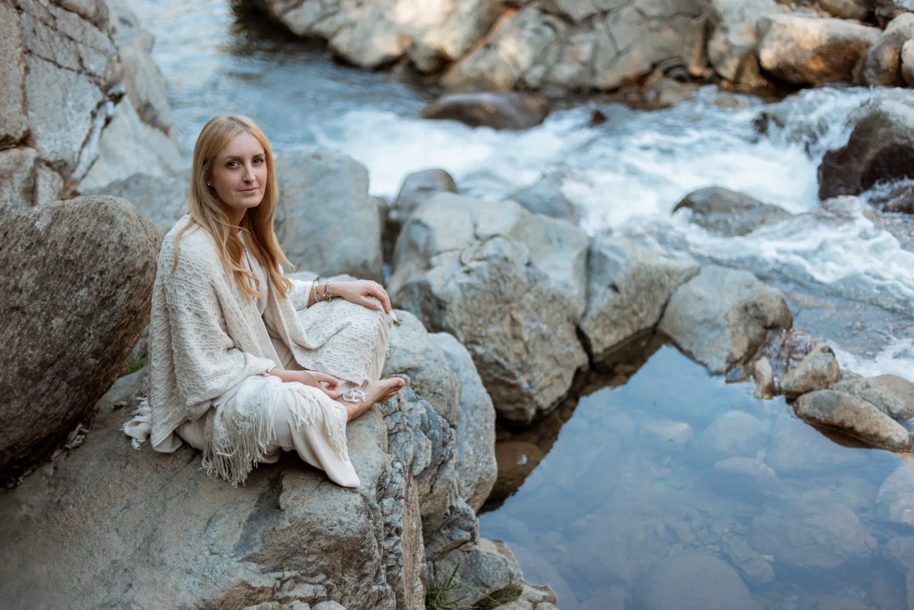Ritratto di donna seduta sulle rocce accanto a un ruscello