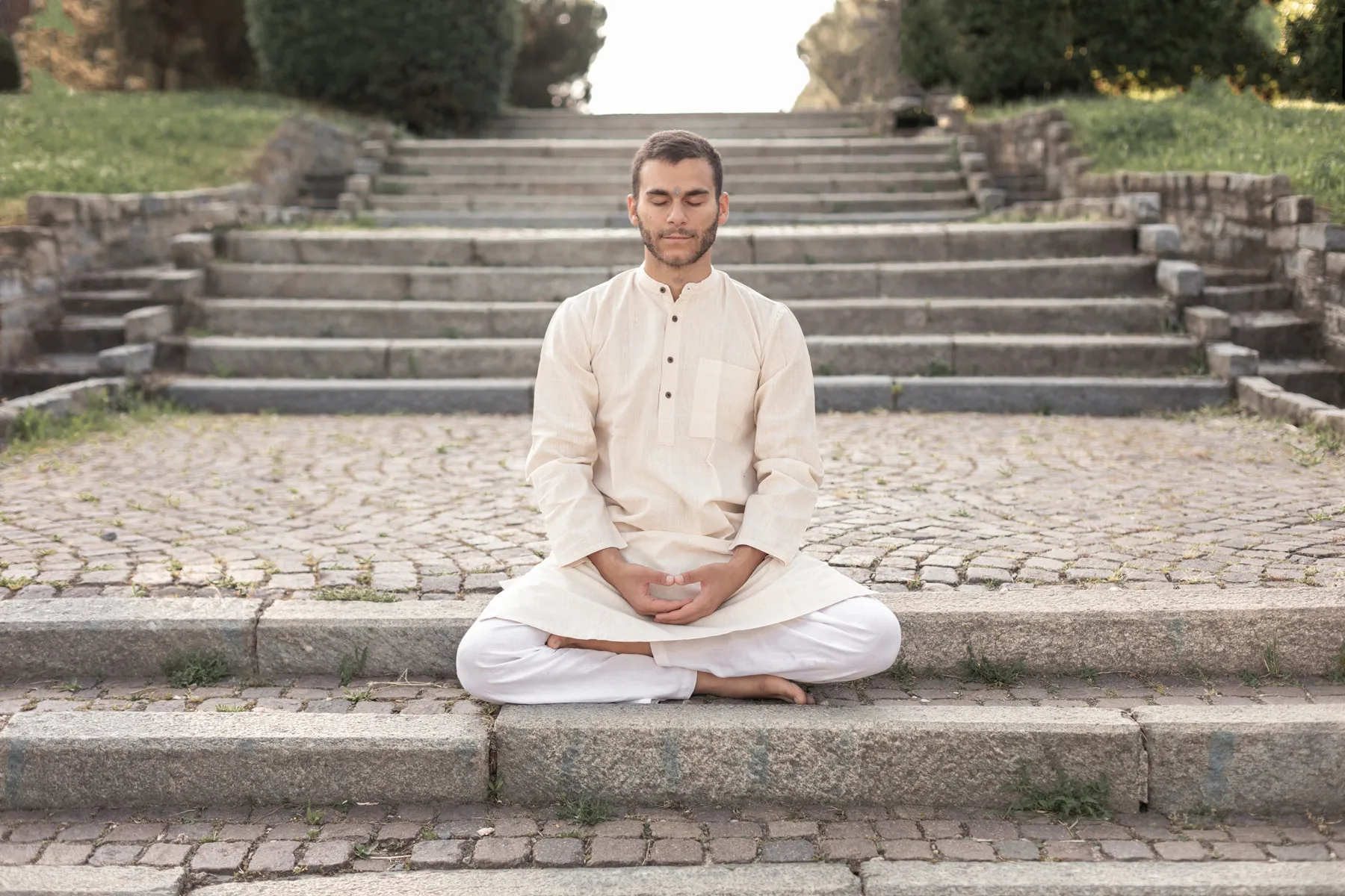 Uomo seduto in meditazione all’aperto davanti a una scalinata