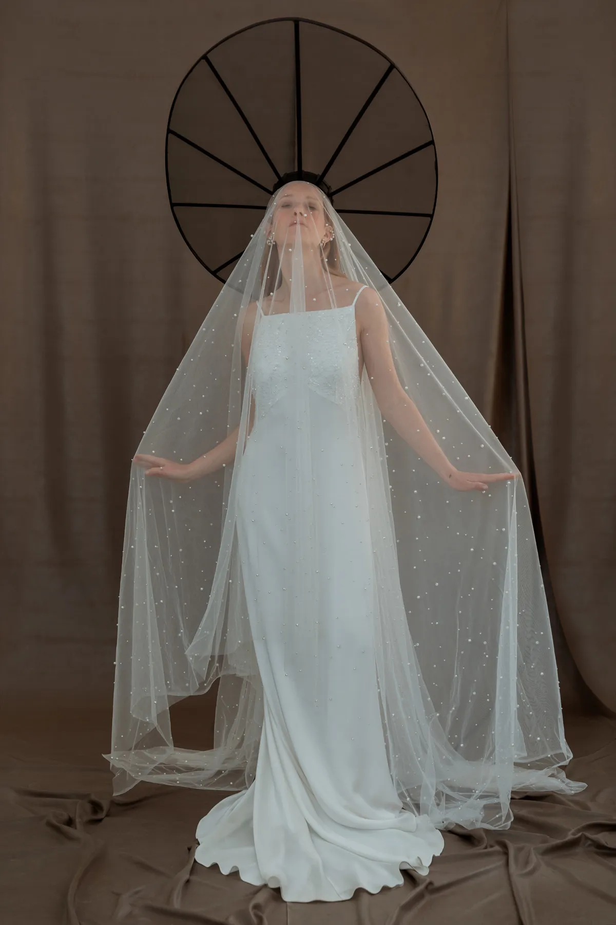 Shooting fashion sposa con velo Modella con abito da sposa e lungo velo fotografata su fondale neutro