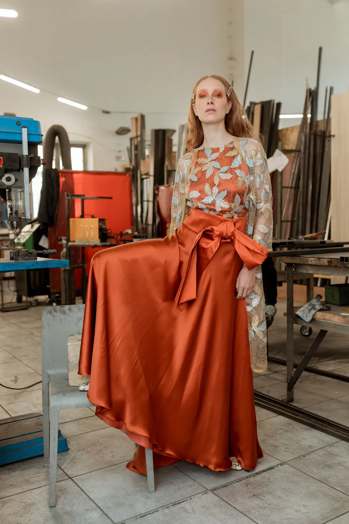 Shooting moda con outfit arancione Modella con outfit arancione fotografata in un ambiente industriale durante uno shooting moda