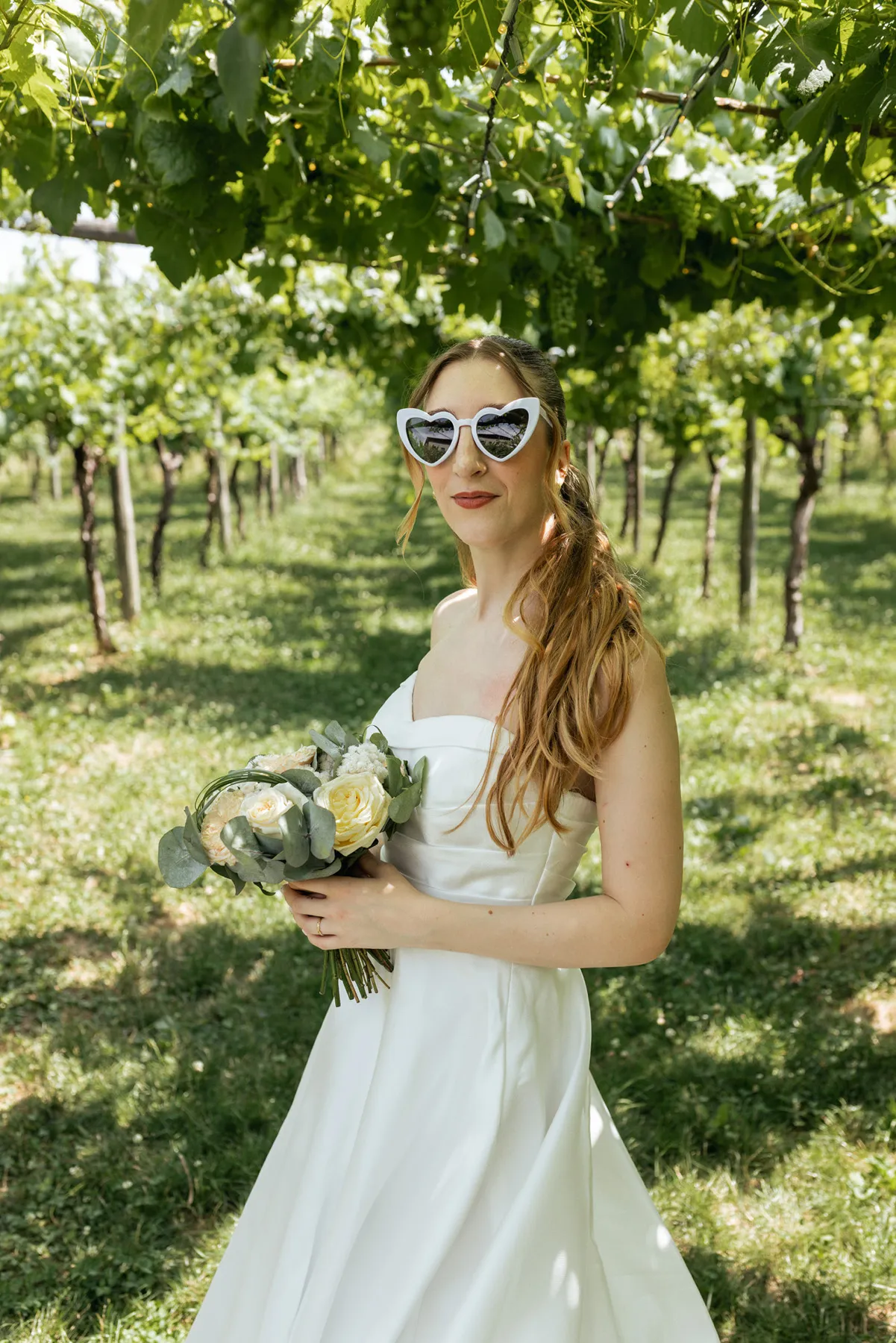 Ritratto della sposa nel vigneto Sposa con bouquet fotografata tra i filari della vigna