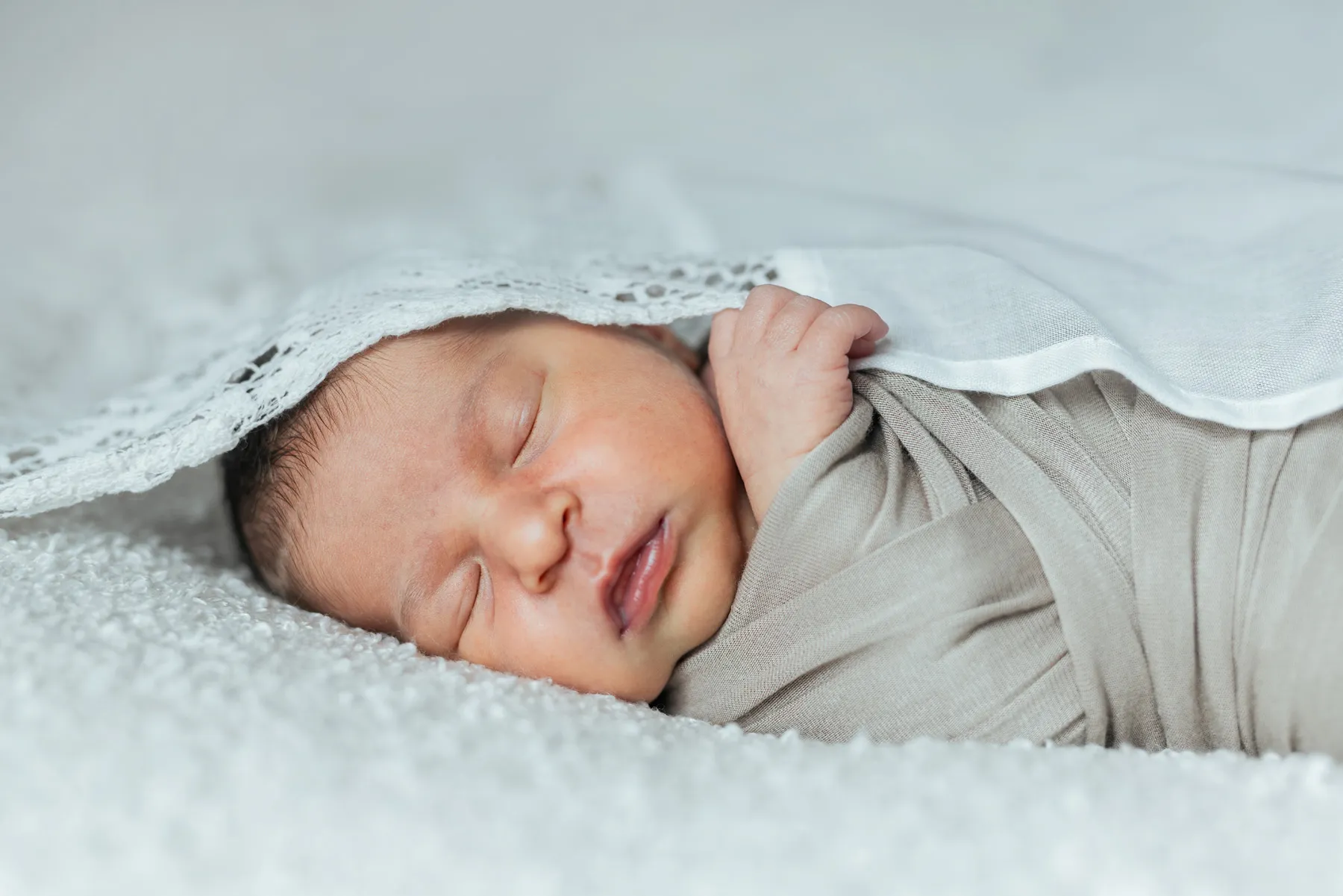 Neonato addormentato avvolto in una copertina durante un servizio fotografico a casa