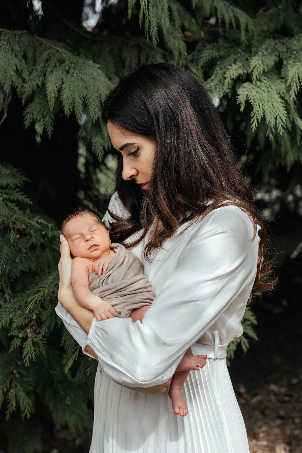 Mamma con il neonato in braccio fotografata nel verde