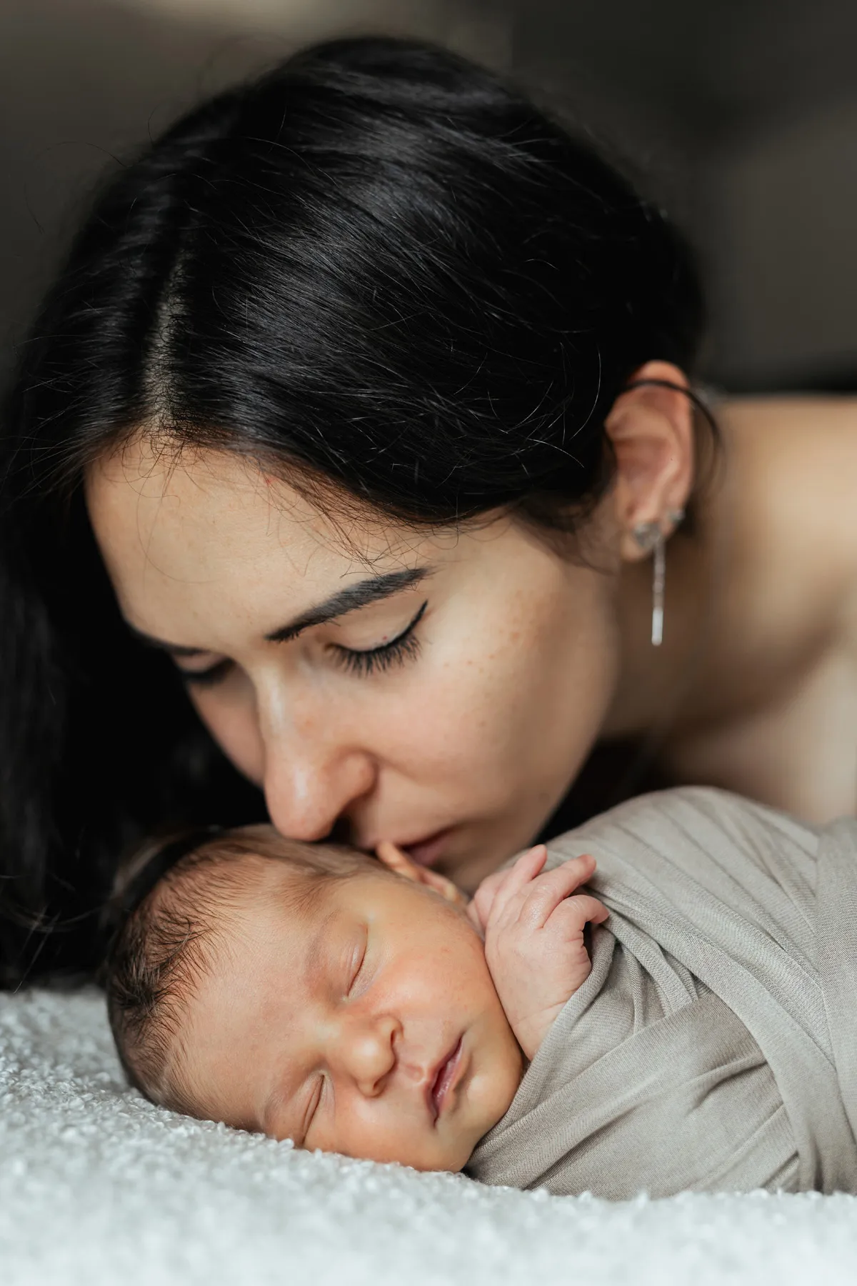 Mamma bacia il suo neonato durante un servizio fotografico newborn