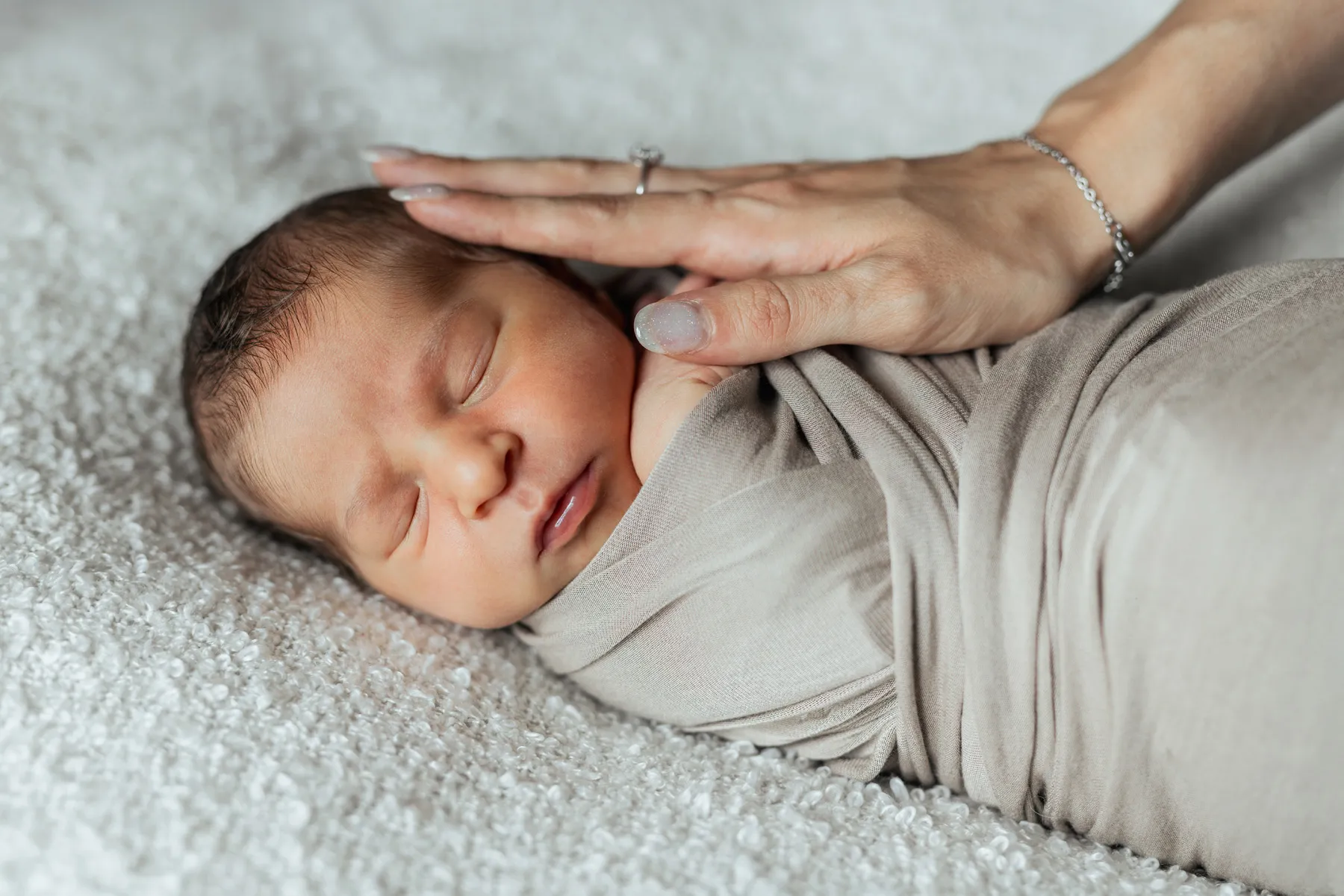 Neonato addormentato mentre la mamma gli accarezza la testa