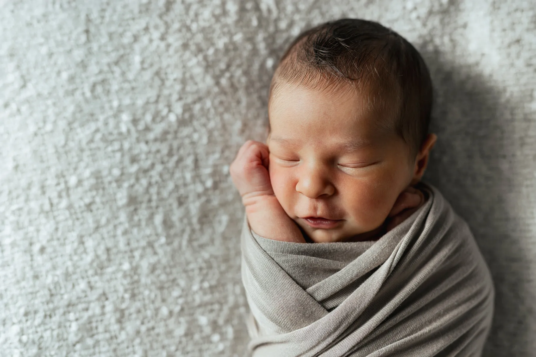 Neonato addormentato avvolto in una copertina durante il servizio newborn