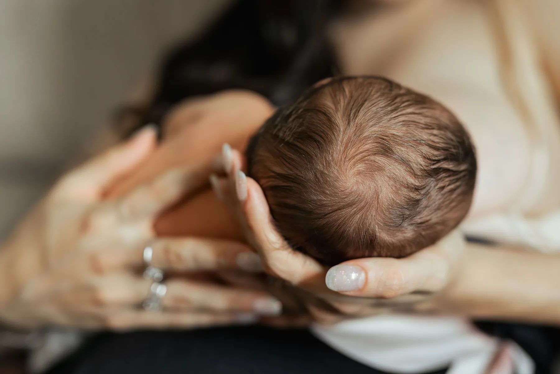 Neonato tra le mani della mamma durante un servizio fotografico newborn a casa